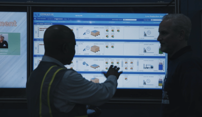 Two men reviewing a warehouse management system on a monitor